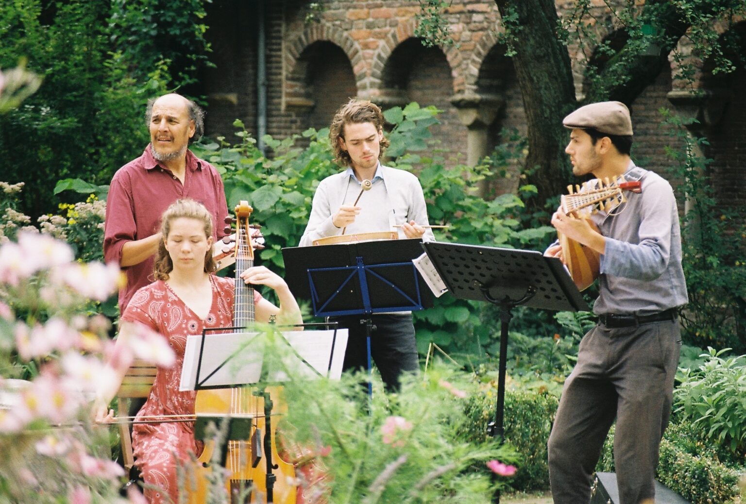 Musici met gamba, luit en trom in een kloostertuin